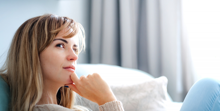 femme souriante et pensive sur l'herbe