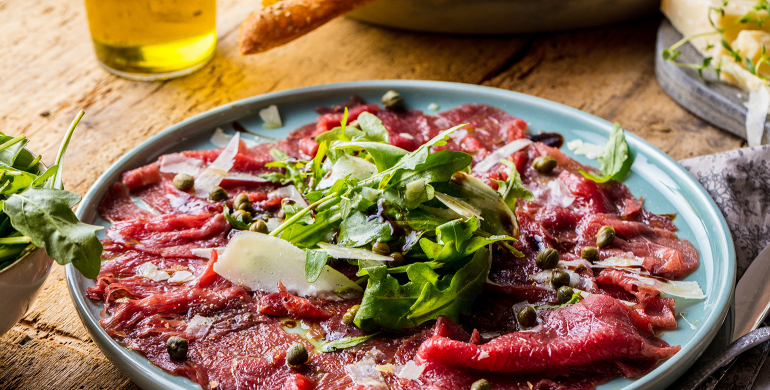 Assiette de carpaccio de boeuf accompagné d'huile d'olive,roquette,parmesan