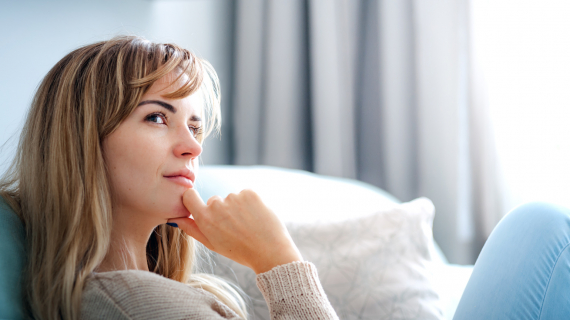 femme souriante et pensive sur l'herbe