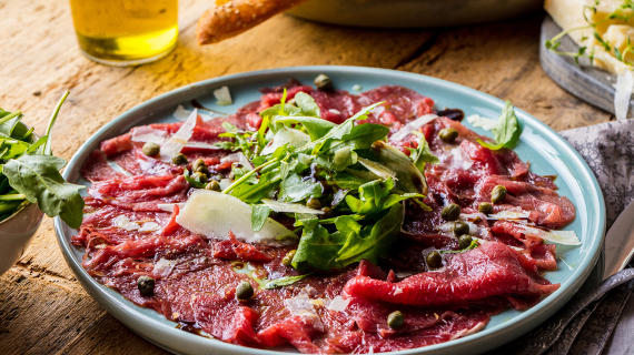 Assiette de carpaccio de boeuf accompagné d'huile d'olive,roquette,parmesan