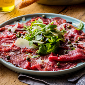 Assiette de carpaccio de boeuf accompagné d'huile d'olive,roquette,parmesan